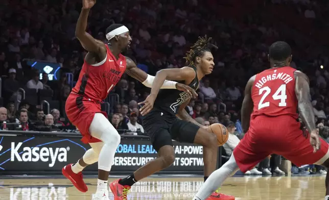 Miami Heat center Bam Adebayo, left, defends Brooklyn Nets forward Noah Clowney, center, during the first half of an NBA basketball game, Monday, Dec. 23, 2024, in Miami. (AP Photo/Lynne Sladky)