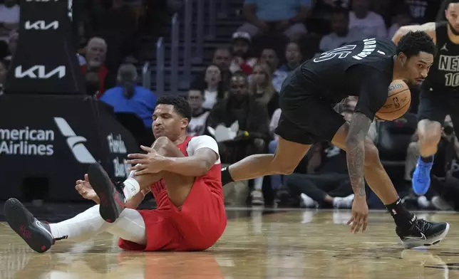 Miami Heat guard Dru Smith, left, loses control of the ball as Brooklyn Nets guard Keon Johnson recovers the ball during the first half of an NBA basketball game, Monday, Dec. 23, 2024, in Miami. (AP Photo/Lynne Sladky)