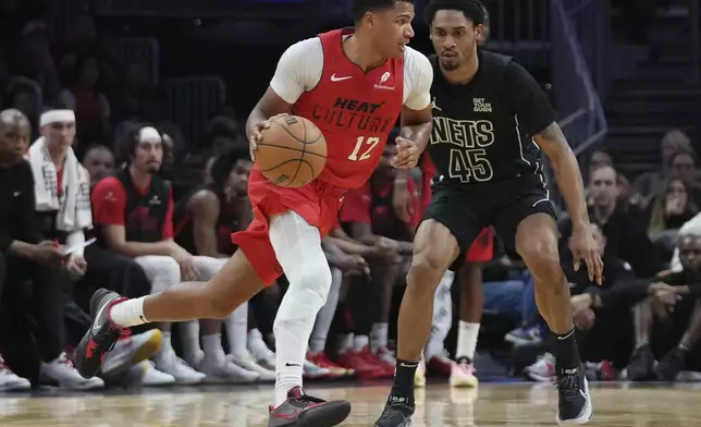 Miami Heat guard Dru Smith (12) dribbles as Brooklyn Nets guard Keon Johnson (45) defends during the first half of an NBA basketball game, Monday, Dec. 23, 2024, in Miami. (AP Photo/Lynne Sladky)