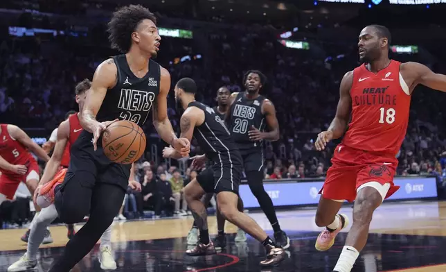 Brooklyn Nets center Nic Claxton, left, dribbles the ball as Miami Heat guard Alec Burks (18) defends during the first half of an NBA basketball game, Monday, Dec. 23, 2024, in Miami. (AP Photo/Lynne Sladky)