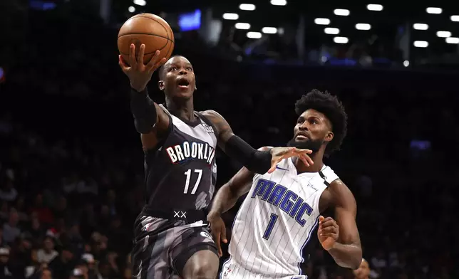 Brooklyn Nets guard Dennis Schroder (17) drives to the basket against Orlando Magic forward Jonathan Isaac (1) during the first half of an NBA basketball game, Sunday, Dec. 1, 2024, in New York. (AP Photo/Noah K. Murray)