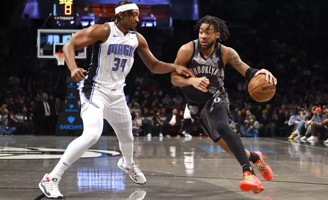 Brooklyn Nets forward Trendon Watford, right, drives to the basket against Orlando Magic center Wendell Carter Jr. (34) during the first half of an NBA basketball game, Sunday, Dec. 1, 2024, in New York. (AP Photo/Noah K. Murray)