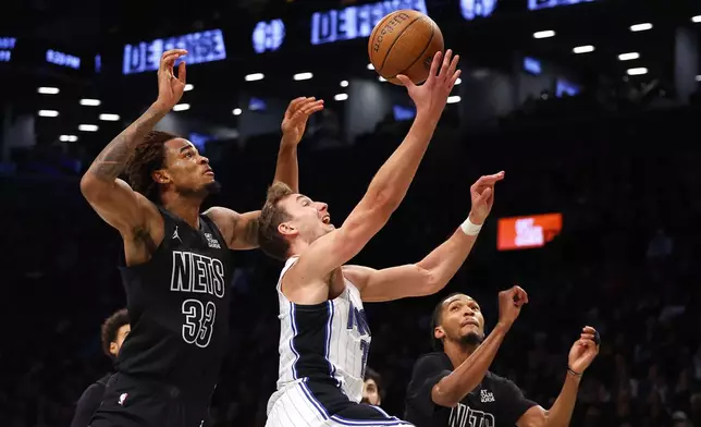 Orlando Magic forward Franz Wagner (22) drives to the basket against Brooklyn Nets center Nic Claxton (33) and forward Ziaire Williams (1) during the first half of an Emirates NBA Cup basketball game, Friday, Nov. 29, 2024, in New York. (AP Photo/Noah K. Murray)