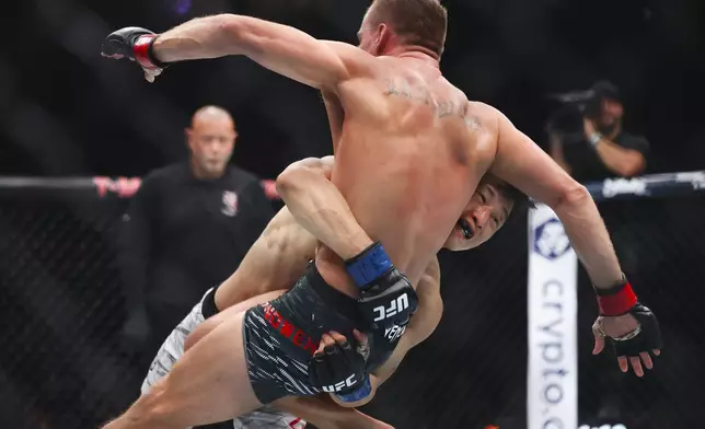 Dooho Choi, right, takes down Nate Landwehr, top, in a UFC 310 mixed martial arts featherweight bout at T-Mobile Arena, Saturday, Dec. 7, 2024, in Las Vegas. (Wade Vandervort/Las Vegas Sun via AP)