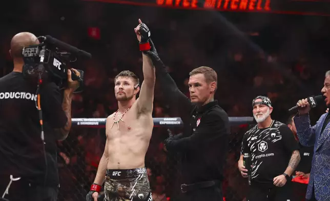 Bryce Mitchell, center left, stands in the octagon after defeating Kron Gracie in a UFC 310 mixed martial arts featherweight bout at T-Mobile Arena, Saturday, Dec. 7, 2024, in Las Vegas. (Wade Vandervort/Las Vegas Sun via AP)