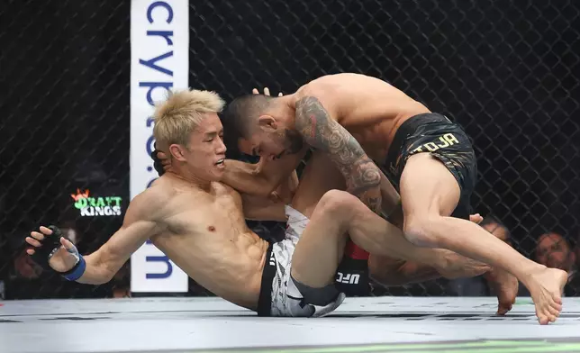 Alexandre Pantoj, right, grapples with Kai Asakura in a UFC 310 mixed martial arts flyweight title bout at T-Mobile Arena, Saturday, Dec. 7, 2024, in Las Vegas. (Wade Vandervort/Las Vegas Sun via AP)