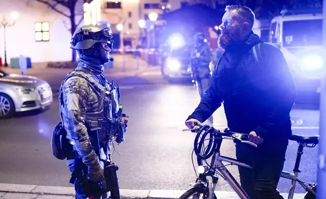 A police officer speaks with a man at a cordoned-off area near a Christmas Market after an incident in Magdeburg, Germany, Friday, Dec. 20, 2024. (AP Photo/Ebrahim Noroozi)