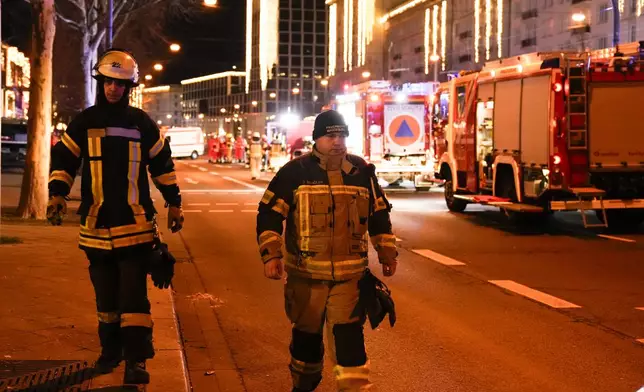 Two firefighters walk through a cordoned-off area near a Christmas Market, after a car drove into a crowd in Magdeburg, Germany, Saturday, Dec. 21, 2024. (AP Photo/Ebrahim Noroozi)