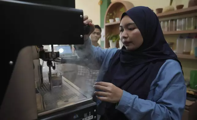 Qurrata Ayuni, a 28-year-old tsunami survivor, operates a coffee machine at the cafe she runs in Banda Aceh, Indonesia, Wednesday, Dec. 11, 2024. (AP Photo/Achmad Ibrahim)