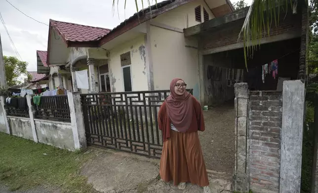 Qurrata Ayuni, a 28-year-old tsunami survivor, stands outside her house, built on the same spot where her parents' home once stood before it was destroyed by the disaster in 2004 in Lampuuk on the outskirts of Banda Aceh, Indonesia, Friday, Dec. 13, 2024. (AP Photo/Achmad Ibrahim)