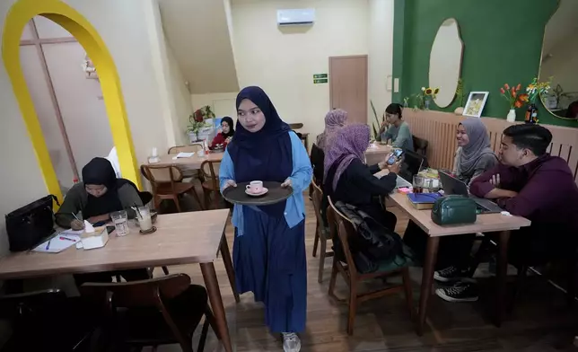 Qurrata Ayuni, a 28-year-old tsunami survivor, serves customers at the cafe she runs in Banda Aceh, Indonesia, Wednesday, Dec. 11, 2024. (AP Photo/Achmad Ibrahim)