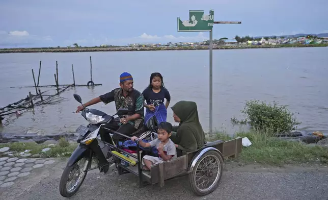 A family aride on a motorized tricycle on Ulee Lheue beach, one of the ares hardest hit by the Indian Ocean tsunami in 2004, in Banda Aceh, Indonesia, Friday, Dec. 13, 2024. (AP Photo/Achmad Ibrahim)