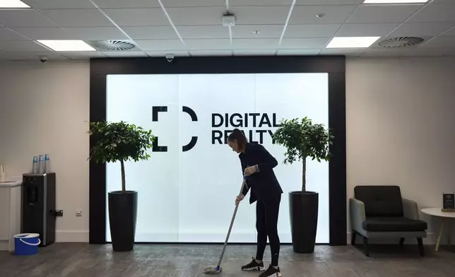 A cleaner mops the floor in the reception hall of an empty data center building, in Dublin, Ireland, Thursday, Oct. 17, 2024. (AP Photo/Bram Janssen)