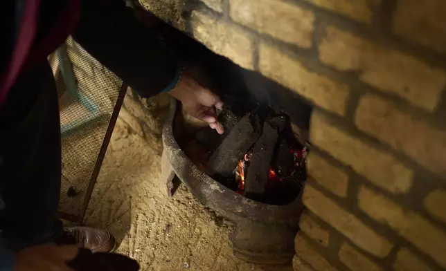 A local activist opposing the construction of wind farms burns peat in a fireplace, in Lemanaghan, Ireland, Wednesday, Oct. 16, 2024. (AP Photo/Bram Janssen)