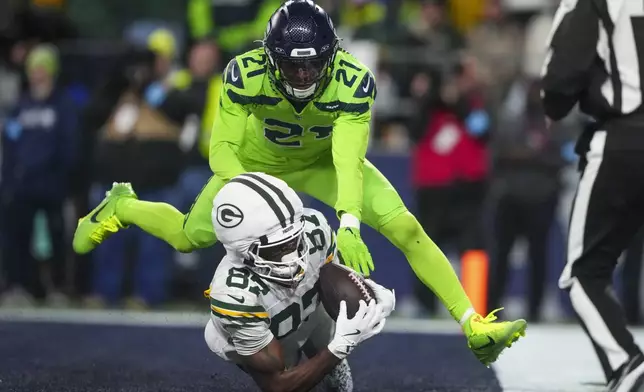 Green Bay Packers' Romeo Doubs catches a touchdown pass in front of Seattle Seahawks' Devon Witherspoon during the second half of an NFL football game Sunday, Dec. 15, 2024, in Seattle. (AP Photo/Lindsey Wasson)