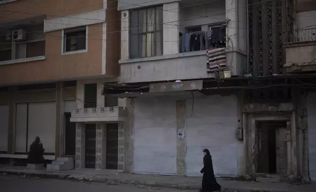 A woman walks on a street in an Alawite neighbourhood, in Homs, Syria, Thursday, Dec. 26, 2024. (AP Photo/Leo Correa)