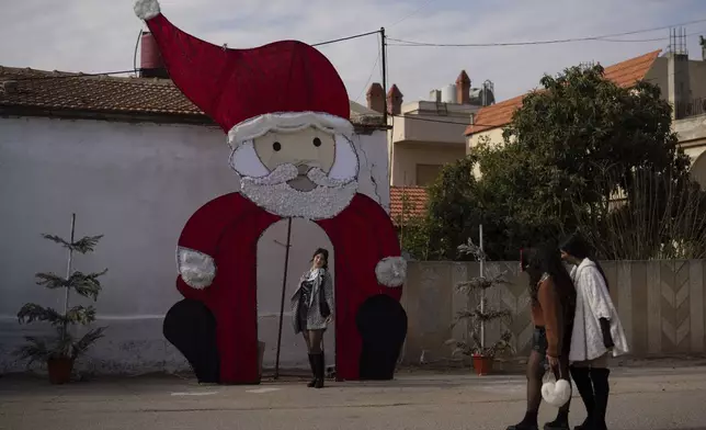 A young woman poses for a picture with a Christmas decoration on a square in a Christian neighbourhood, in Homs, Syria, Thursday, Dec. 26, 2024. (AP Photo/Leo Correa)