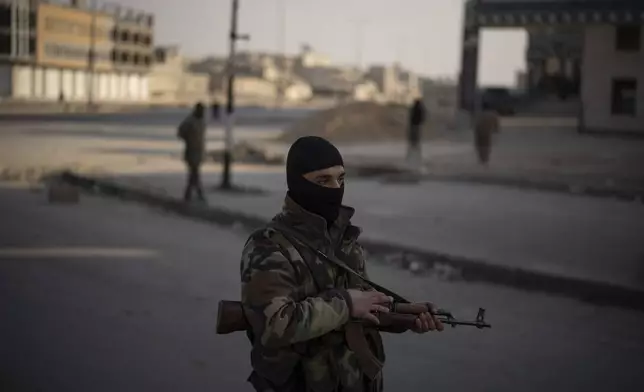 A member of the security forces of the newly formed Syrian government stands on guard at a security checkpoint, in Homs, Syria, Thursday, Dec. 26, 2024. (AP Photo/Leo Correa)