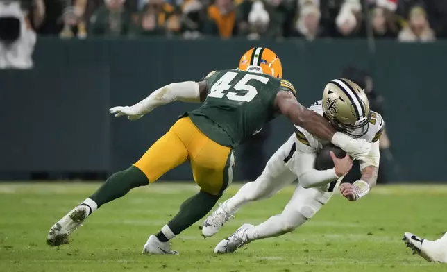 Green Bay Packers linebacker Eric Wilson (45) stops New Orleans Saints quarterback Spencer Rattler (18) on a carry during the first half of an NFL football game, Monday, Dec. 23, 2024, in Green Bay, Wis. (AP Photo/Morry Gash)
