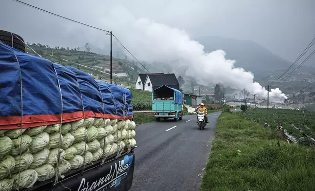 Steam rises from a geothermal power plant as a motorist rides past by in Dieng, Central Java, Indonesia, Nov. 15, 2024. (AP Photo/Beawiharta)