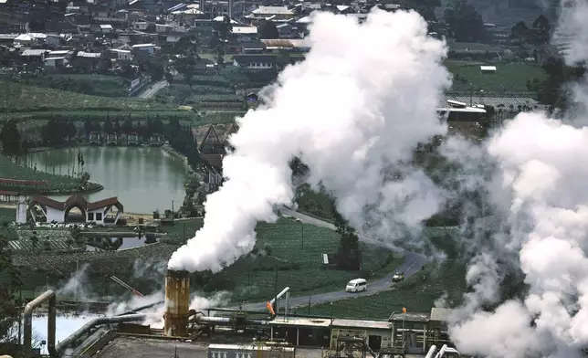 Cars drive on a road as steam rises from a geothermal power plant in Dieng, Central Java, Indonesia, Nov. 15, 2024. (AP Photo/Beawiharta)