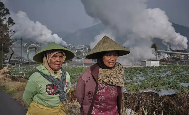 Farmers walk by as steam rises from a geothermal power plant in Dieng, Central Java, Indonesia, Nov. 15, 2024. (AP Photo/Beawiharta)