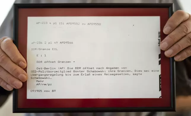 FILE -In this Oct. 31, 2019 photo, Frieder Reimold the former Berlin bureau chief of The Associated Press' German service shows the original print from the iconic Associated Press German service news alert, "DDR oeffnet Grenze," or "East Germany opens border" in Stansdorf near Berlin. (AP Photo/Markus Schreiber, File)