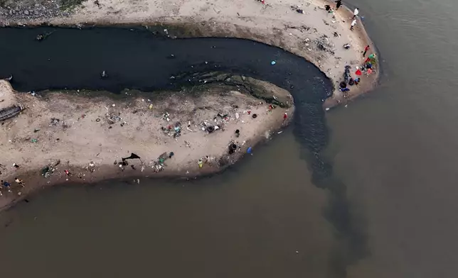 People fish next to drainage that flows into the Paraguay River in Asuncion, Paraguay, on Jan. 28, 2024. (AP Photo/Jorge Saenz)