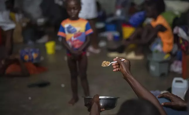 A mother coaxes her daughter into trying a spoonful of rice at a school turned into a makeshift shelter for people displaced by gang violence, in Port-au-Prince, Haiti, on May 8, 2024. (AP Photo/Ramon Espinosa)