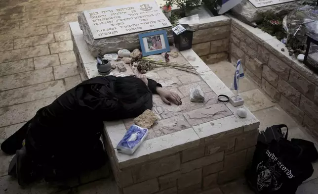 Sara Chen weeps over the grave of her longtime friend, Staff Sgt. Avraham Nerya Cohen, who was killed in action on Oct. 7, 2023, as Israel marks the first anniversary of the Hamas attack on Israel, at the Mount Herzl military cemetery in Jerusalem on Oct. 7, 2024. (AP Photo/Maya Alleruzzo)