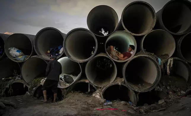 A man sits inside a concrete pipe meant for municipal use after his shelter was swept away by the flooding Bagmati River in Kathmandu, Nepal, on Oct. 1, 2024. (AP Photo/Niranjan Shrestha)