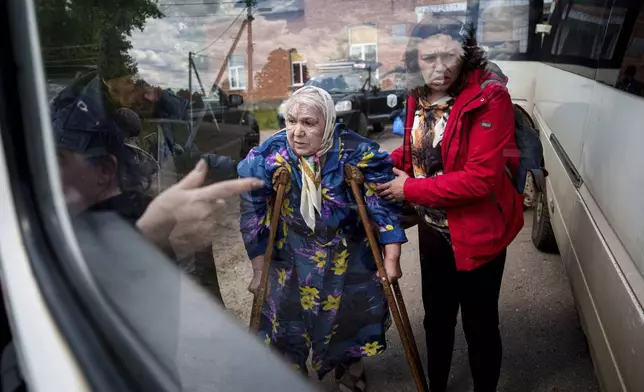 People help Liudmila, 85, board a bus after their evacuation from Vovchansk, Ukraine, on May 12, 2024. Her husband was killed in their house during a Russian airstrike on the city. (AP Photo/Evgeniy Maloletka)