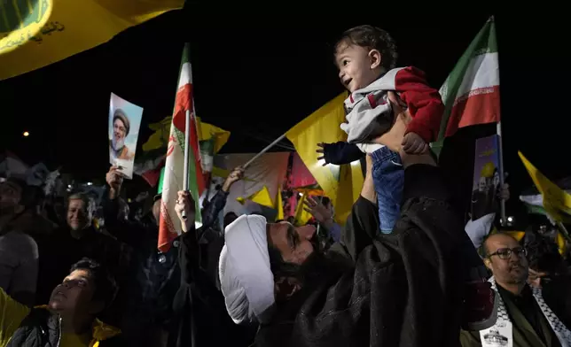 A cleric holds up his son as he celebrates Iran's missile strike against Israel during an anti-Israeli protest at Felestin (Palestine) Square in Tehran, Iran, on Oct. 1, 2024. (AP Photo/Vahid Salemi)