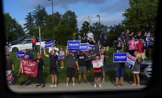 Supporters of Republican presidential candidate former President Donald Trump hold signs as Democratic presidential nominee Vice President Kamala Harris passes by on her bus en route to a campaign stop at the Primanti Bros. restaurant in Pittsburgh, on Aug. 18, 2024. (AP Photo/Julia Demaree Nikhinson)