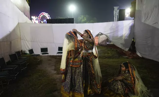 Actors make final adjustments to their costumes before the start of Ramleela, a dramatic folk re-enactment of the life of Rama according to the ancient Hindu epic Ramayana, in New Delhi, India, on Oct. 5, 2024. (AP Photo/Manish Swarup)