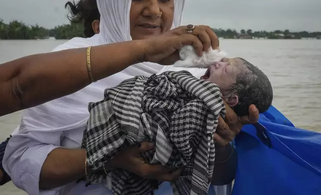 Midwife Diluwara Begum holds a newborn baby girl after helping deliver her on a boat on the River Brahmaputra, in the northeastern Indian state of Assam, on July 3, 2024. (AP Photo/Anupam Nath)