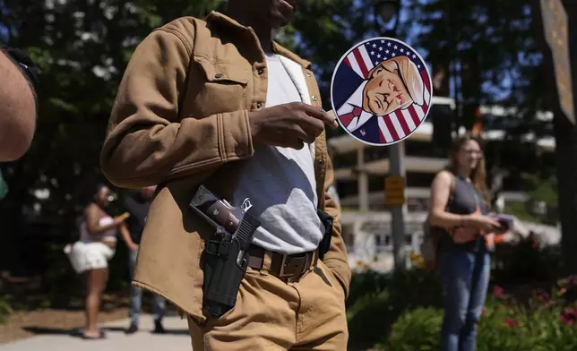 A person carrying a handgun and a sign depicting Republican presidential candidate former President Donald Trump stands outside the Republican National Convention in Milwaukee on July 18, 2024. (AP Photo/Jae C. Hong)