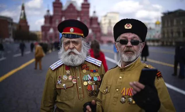 Two men in Russian Cossack uniforms pose for a selfie with the Historical Museum in the background after visiting the mausoleum of the Soviet founder Vladimir Lenin, marking the 154th anniversary of his birth, in Moscow's Red Square, on April 22, 2024. (AP Photo/Alexander Zemlianichenko)