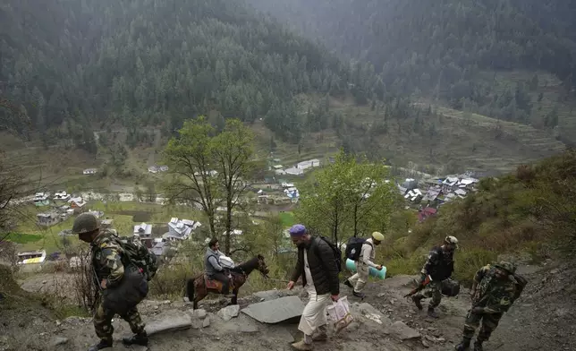 A man transports an electronic voting machine on a pony as election officials walk to a polling booth in a remote mountain area on the eve of the first round of voting in the six-week long national election at Dessa village in Doda district, Jammu and Kashmir, India, April 18, 2024. (AP Photo/Channi Anand)