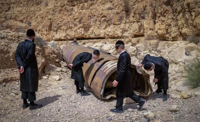 Ultra-Orthodox Jews look at part of an intercepted ballistic missile that fell in the desert near the city of Arad, Israel, on April 28, 2024. (AP Photo/ Ohad Zwigenberg)