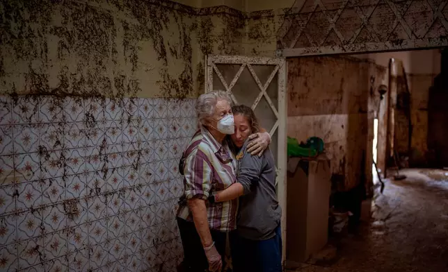 Vero Almarche, right, hugs her neighbor Maria Munoz, who was born in the house where they are photographed and which was destroyed by flooding in Masanasa, Valencia, Spain, on Nov. 6, 2024. (AP Photo/Emilio Morenatti)