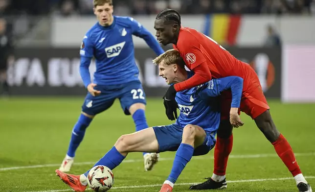 Hoffenheim's Max Moerstadt and Bucharest's Joyskim Dawa, rightm, in action during the Europa League opening phase soccer match between TSG 1899 Hoffenheim and FCSB Bucharest at PreZero Arena, Sinsheim, Germany, Thursday Dec. 12 2024. (Uwe Anspach/dpa via AP)