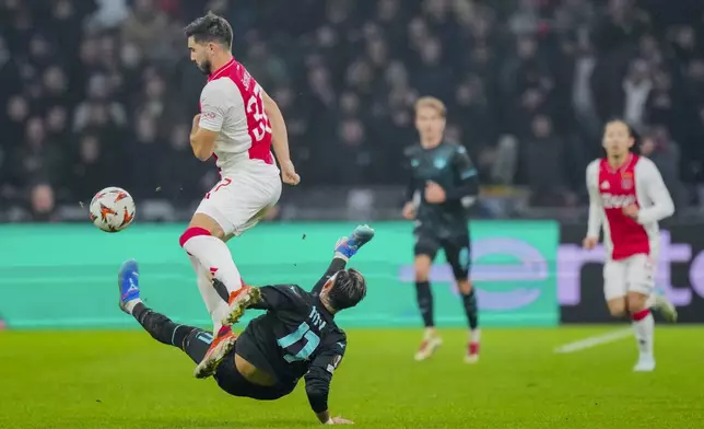 Ajax's Josip Sutalo duels for the ball with Lazio's Taty Castellanos, bottom, during the Europa League soccer match between Ajax and Lazio Roma at the Johan Cruyff Arena in Amsterdam, Netherlands, Thursday, Dec. 12, 2024. (AP Photo/Peter Dejong)