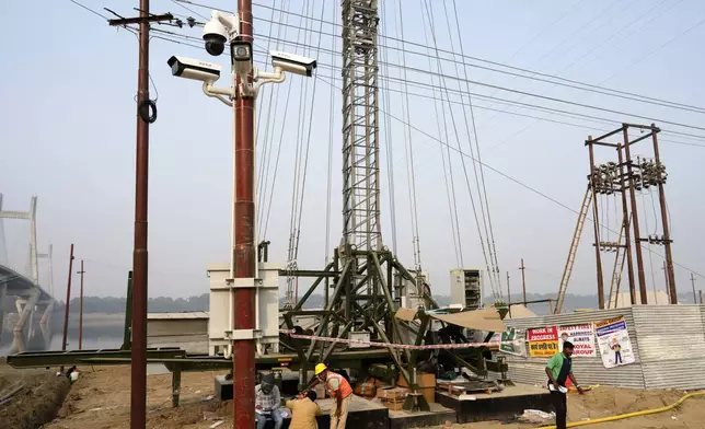 Workers put up electric cables and install surveillance cameras on the banks of the Ganges river in preparation for the upcoming Maha Kumbh Mela, one of the world's largest religious festivals, in Prayagraj, India, Friday, Nov. 29, 2024. (AP Photo/Rajesh Kumar Singh)