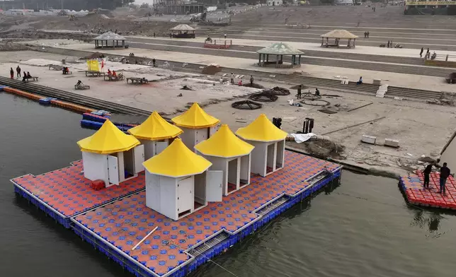 Workers make a floating platform on the Ganges river from interlocking plastic cubes, right, next to a finished one supporting changing rooms for the VIPs, in preparation for the upcoming Maha Kumbh Mela, one of the world's largest religious festivals, in Prayagraj, India, Saturday, Nov. 30, 2024. (AP Photo/Rajesh Kumar Singh)