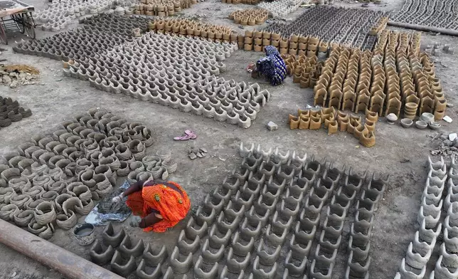 Women make clay stoves to be sold to the devotees who will be staying on the banks of the Ganges river, in preparation for the upcoming Maha Kumbh Mela, one of the world's largest religious festivals, in Prayagraj, India, Monday, Nov. 25, 2024. (AP Photo/Rajesh Kumar Singh)