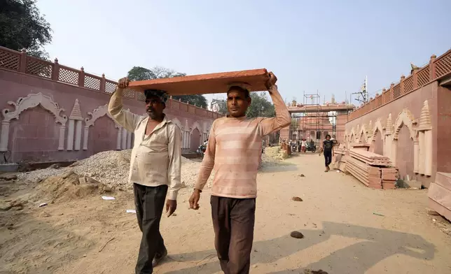 Workers carry a slab of stone to be used for the beautification of a street in preparation for the upcoming Maha Kumbh Mela, one of the world's largest religious festivals, in Prayagraj, India, Sunday, Nov. 24, 2024. (AP Photo/Rajesh Kumar Singh)