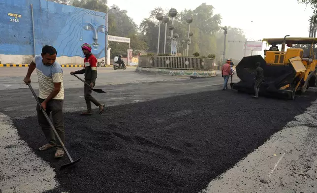 Workers tar a road in preparation for the upcoming Maha Kumbh Mela, one of the world's largest religious festivals, in Prayagraj, India, Sunday, Dec. 1, 2024. (AP Photo/Rajesh Kumar Singh)