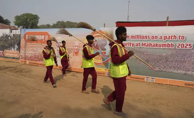 Sanitation workers walk to their work area on the banks of the Ganges river in preparation for the upcoming Maha Kumbh Mela, one of the world's largest religious festivals, in Prayagraj, India, Wednesday, Nov. 27, 2024. (AP Photo/Rajesh Kumar Singh)