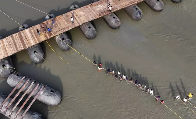 Workers prepare to join a section of a pontoon bridge over the Ganges river in preparation for the upcoming Maha Kumbh Mela, one of the world's largest religious festivals, in Prayagraj, India, Wednesday, Nov. 27, 2024. (AP Photo/Rajesh Kumar Singh)